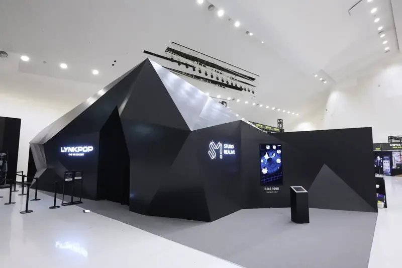 흰 전시장 안에 세운 검은 다면체 모양의 LYNKPOP VR 콘서트 부스